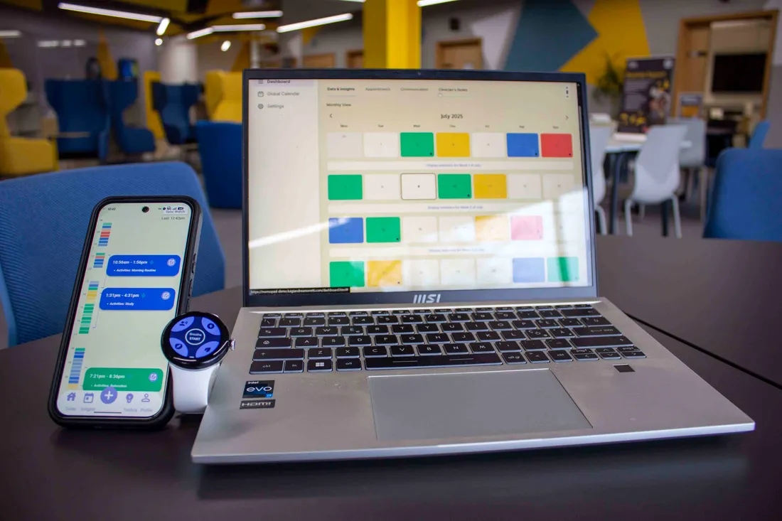MEMoPAD ecosystem desk setup showing clinician web dashboard on laptop, mobile companion app on phone, and Google Pixel Watch 2 smartwatch together