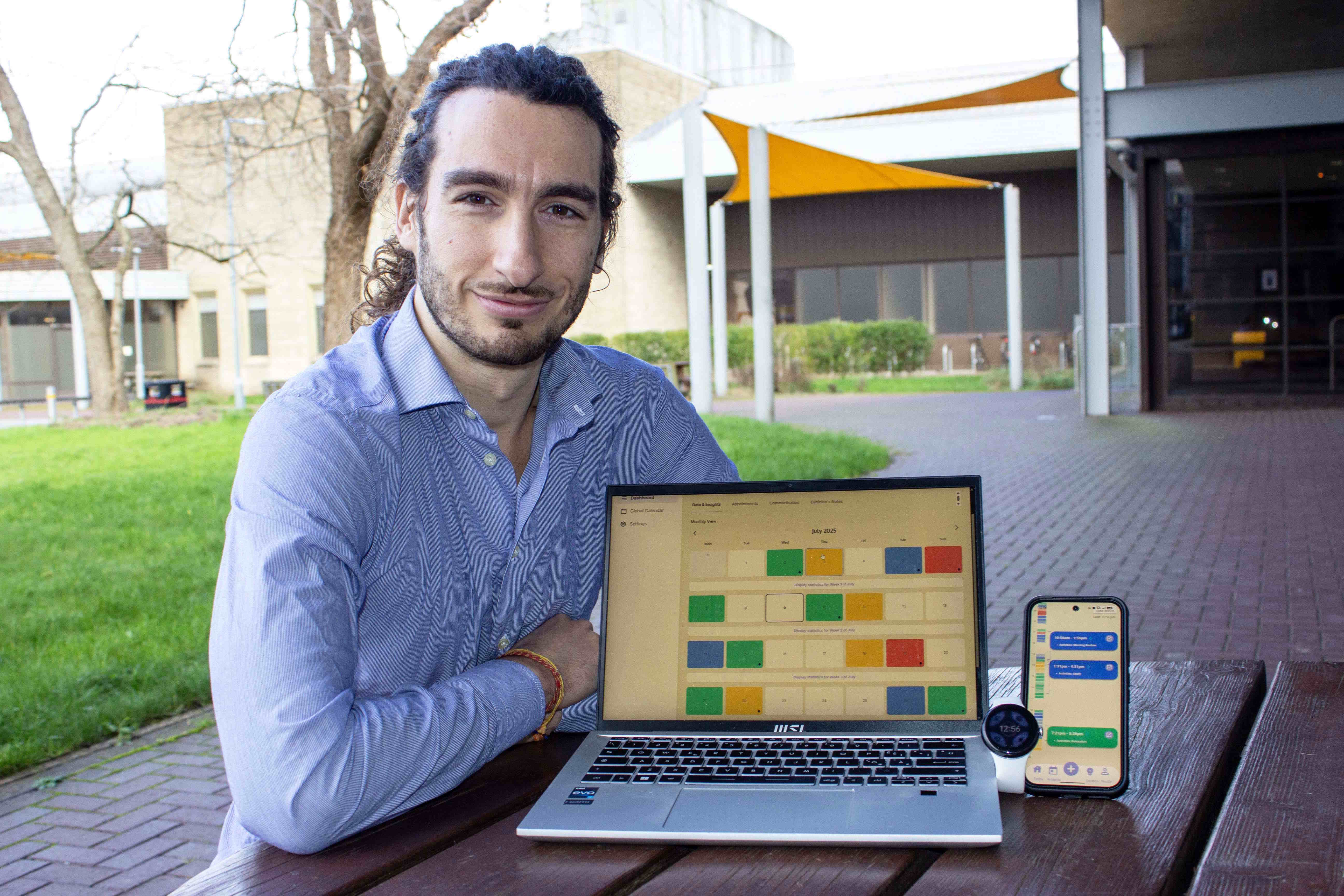 Luigi A. Moretti, PhD candidate at UWE Bristol, sitting outdoors with a laptop showing the MEMoPAD clinician dashboard